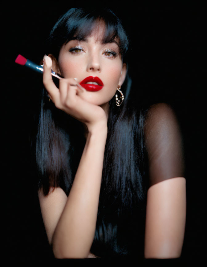 Dark-haired woman applying red lipstick on black background