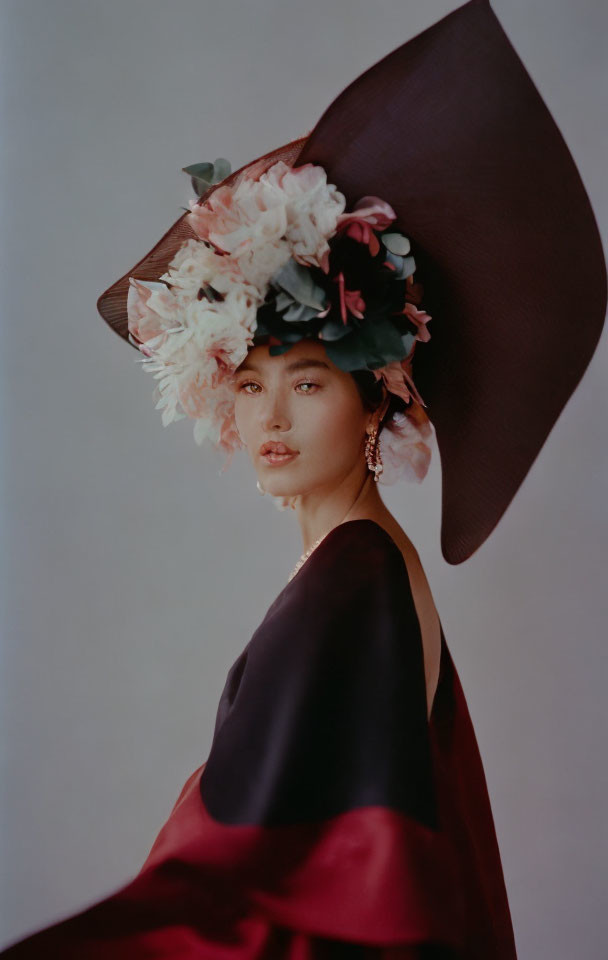 Woman in wide-brimmed hat with flowers and dark shawl, gazing away.