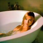 Woman relaxing in bathtub under warm light gaze at camera