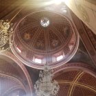 Luxurious interior with grand chandelier under dome ceiling and skylight.