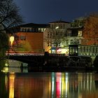 Vibrant nighttime cityscape with colorful buildings, lit bridge, and snowy trees