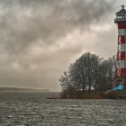 Red lighthouse on rocky outcrop in stormy sea with light rays