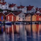 Seaside village at dusk: illuminated windows, boats, wooden piers, seagulls, mo