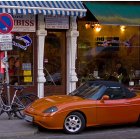 Colorful painting: Vintage car at European café with patrons, bicycle under evening lights