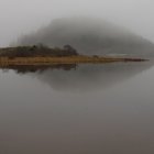 Tranquil lakeside house with misty morning reflections