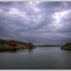 Red Houses on Rocky Islands in Calm Water Under Dramatic Cloudy Sky