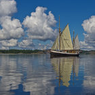 Classic Sailboat with White Sails on Calm Waters and Blue Sky