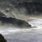 Stormy Coastal Scene: Sea Clashing on Rocky Cliffs with Perilous Houses