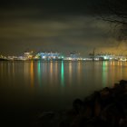 Harbor night scene with tall ships, galaxy sky, calm waters, and lit promenade