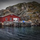 Red Cabin with White Trim on Rocky Terrain by Dark Water Pier