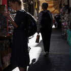 Woman in patterned dress at vibrant market alley admiring colorful pottery