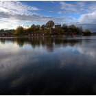 Tranquil dusk scene: serene lake mirrors village houses and lush trees under evening sky