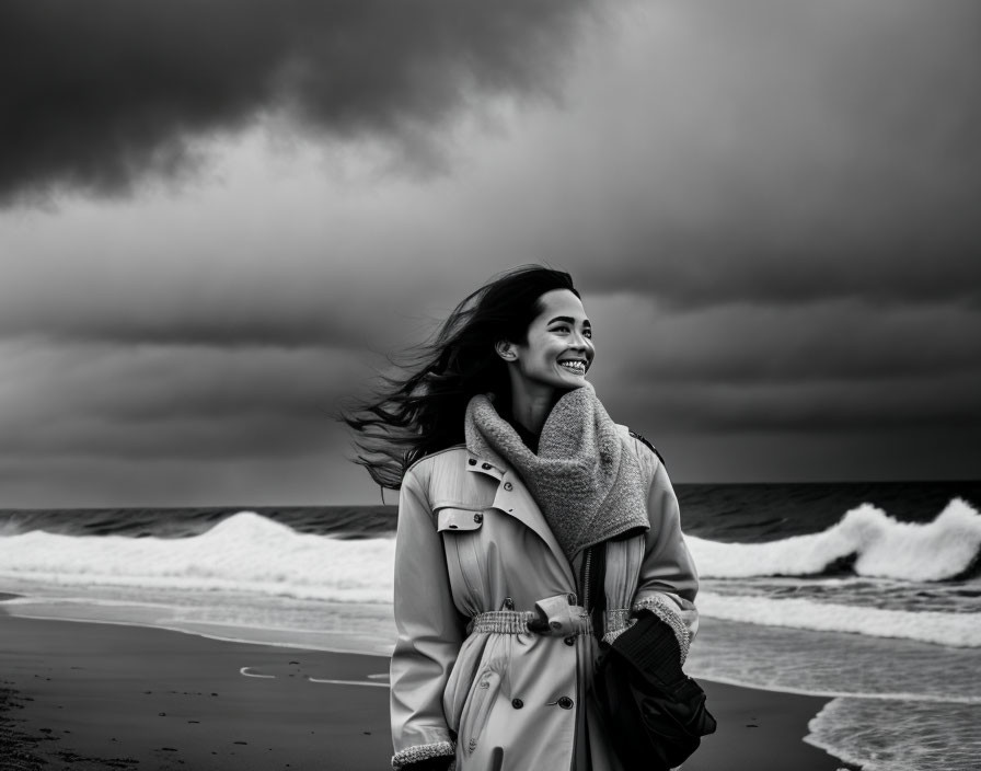 Smiling woman in coat on cloudy beach with waves