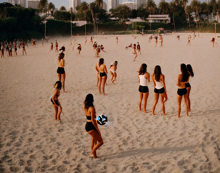 Beach volleyball game at sunset with serving player and spectators