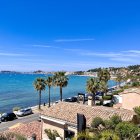 Scenic coastal landscape with shack, sandy path, sea, shrubs, and clear sky