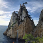 Cliff waterfall cascading into sea with lone tree and dramatic sky