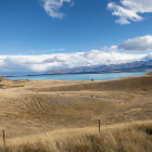 Snow-capped mountains, golden hills, rivers, and blue sky in scenic landscape