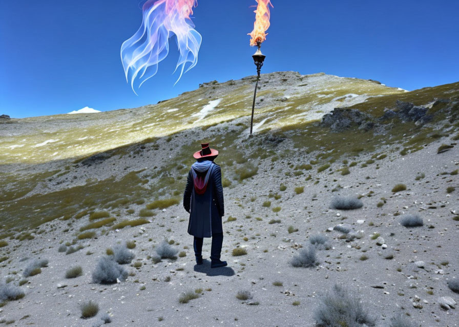 Person in Hat and Cloak Faces Flaming Torch on Grassy Hill