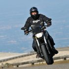 Futuristic person on motorcycle in rugged terrain with snow-capped mountains