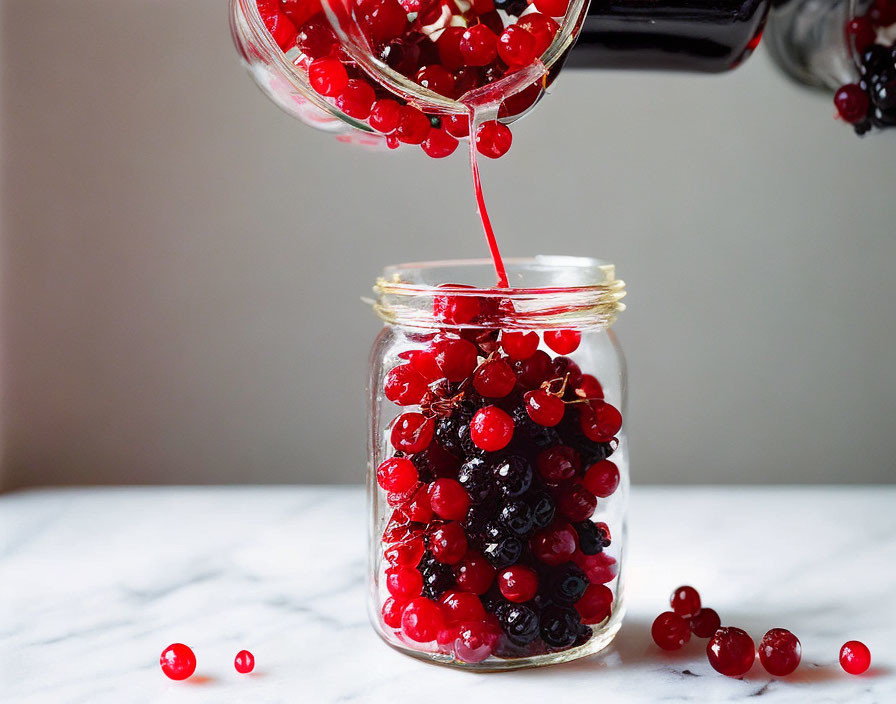 Fresh red currants poured into glass jar on marble surface