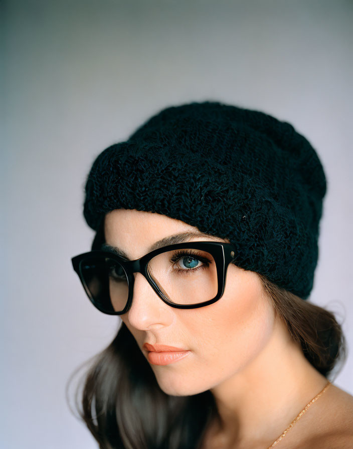 Woman with blue eyes in beanie & glasses, gazing sideways