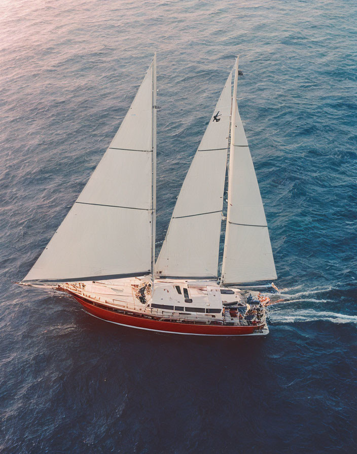 Large Sailing Yacht with Two Tall Masts Sailing on Blue Ocean at Sunset