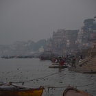 Historical buildings and wooden boats on misty river at dawn