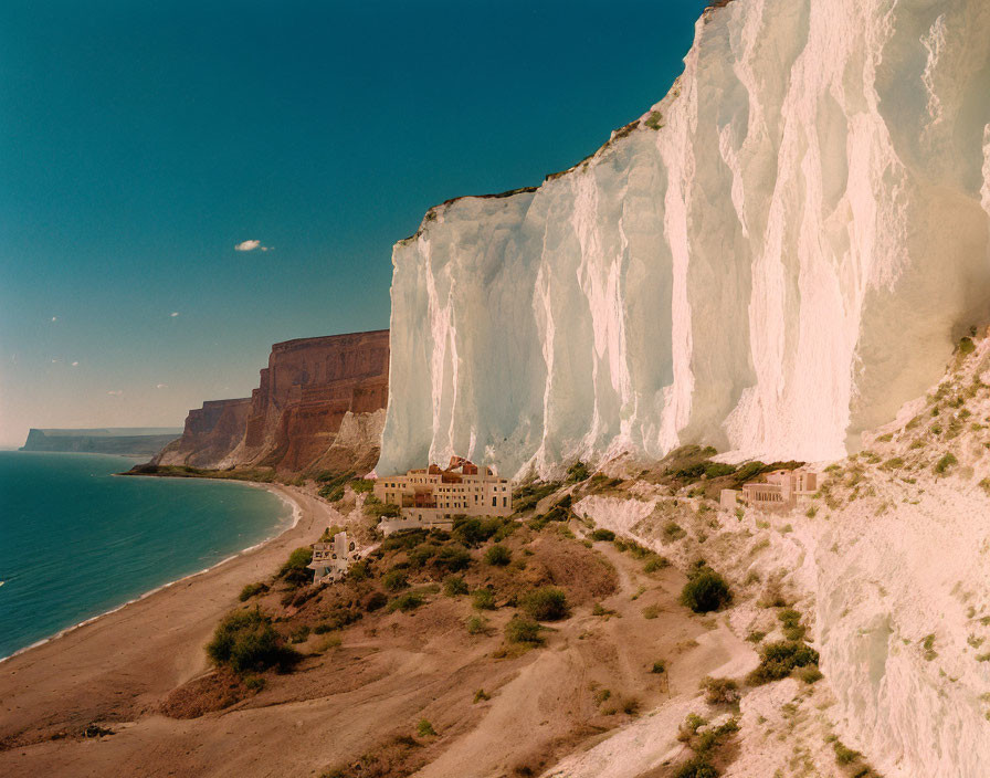 White Cliff Beach with Clear Blue Sea and Small Buildings