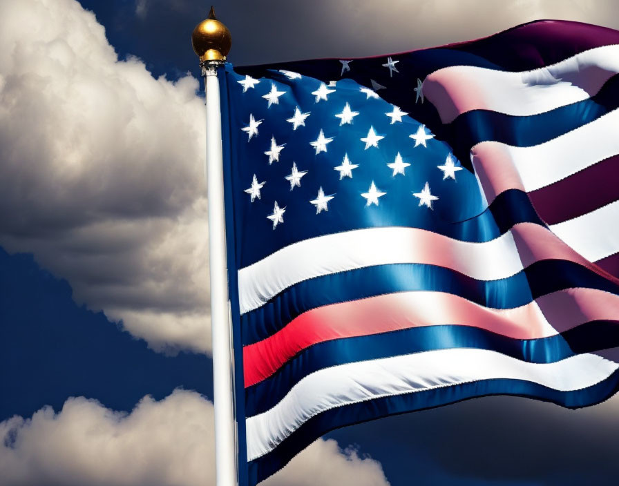 American flag waving under blue sky with fluffy clouds and golden finial