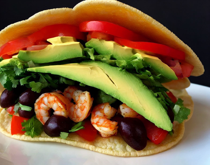 Shrimp taco with avocado, black beans, cilantro, and tomato on corn tortilla