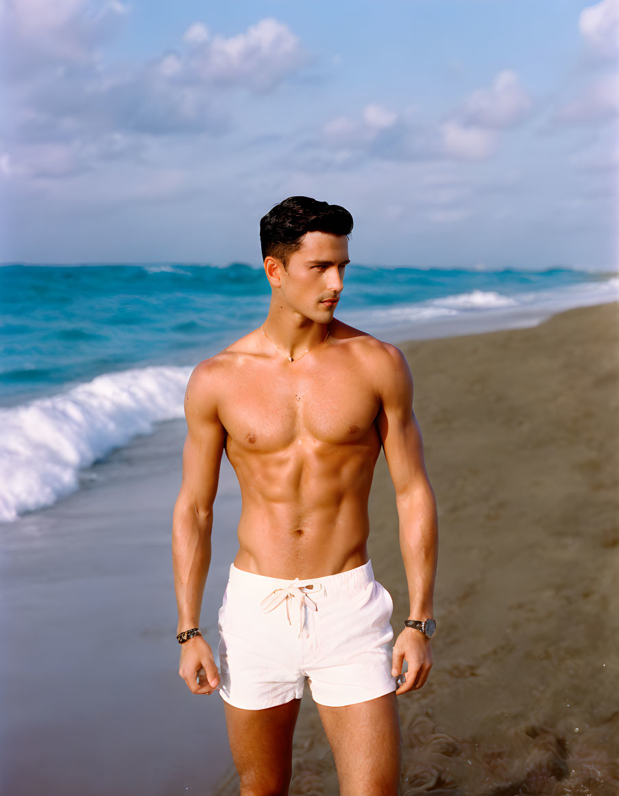 Fit male on beach in white shorts with ocean background