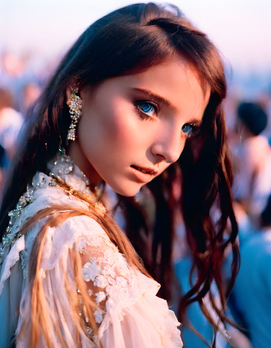 Young woman with blue eyes and brown hair in white lace outfit.