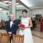 Newlywed couple walking down outdoor aisle with guests and palm trees