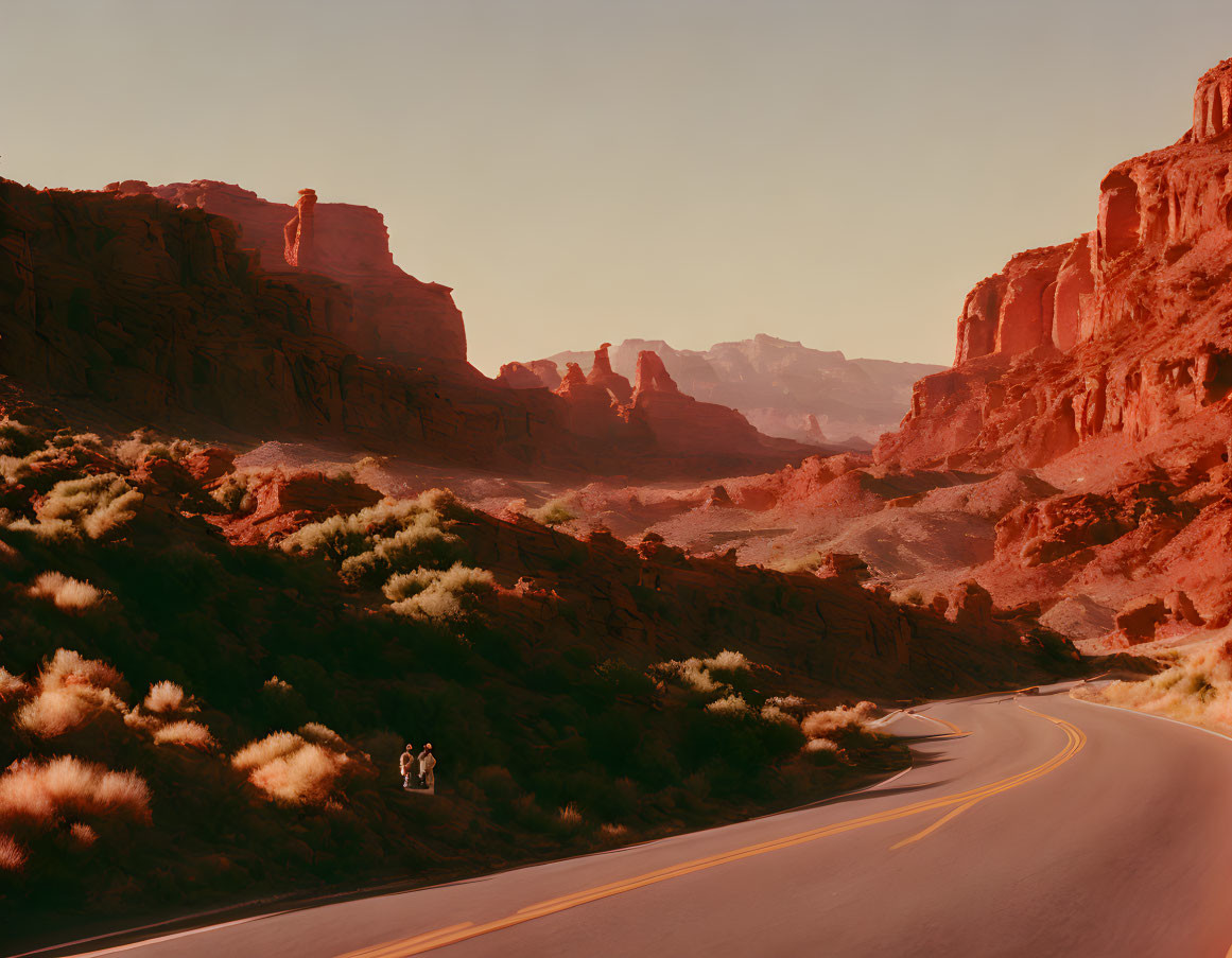 Desert canyon sunset with two people walking near red rock formations