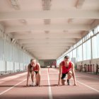 Four individuals performing lunges with dumbbells in misty gym setting