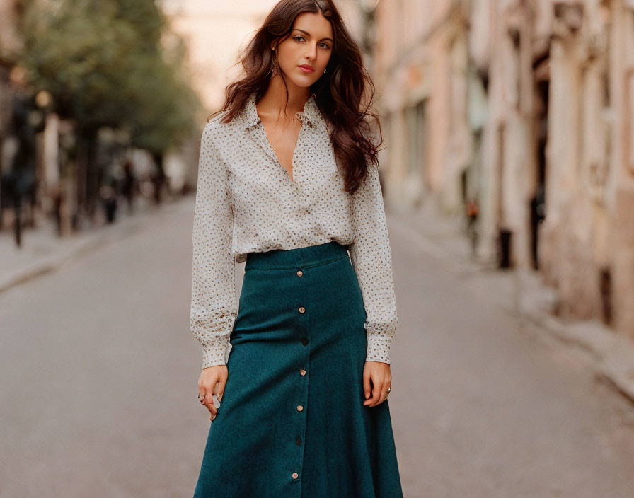 Woman in white blouse and teal skirt on quiet city street