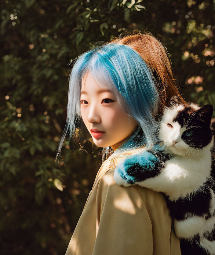 Blue-haired person holding black and white cat in greenery.