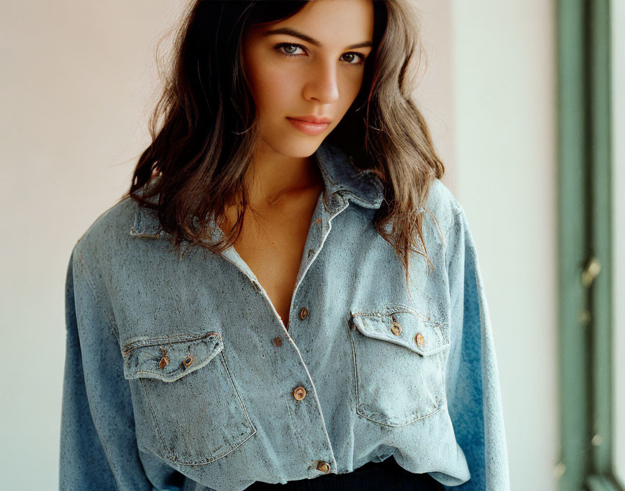 Tousled hair woman in denim shirt gazes at camera