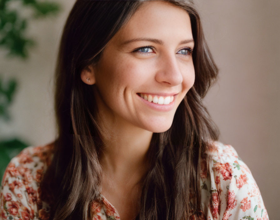 Smiling woman with long hair in floral top indoors