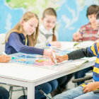 Elementary students using digital tablets around world map background