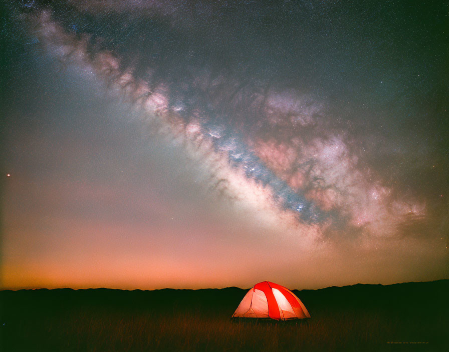 Starry sky with Milky Way over glowing tent