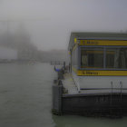 Silhouetted figures on yellow platforms in misty, tiered cityscape