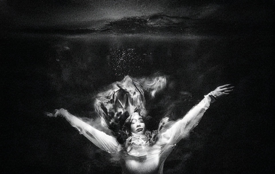 Monochrome underwater photo of person with flowing fabric, creating serene atmosphere