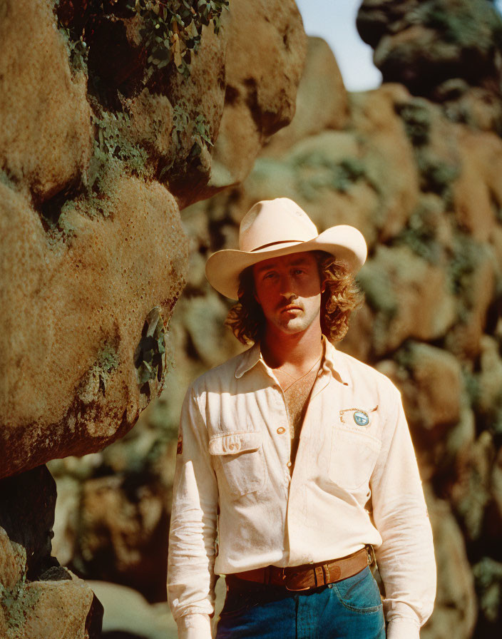 Cowboy hat man in denim against rocky terrain portrait