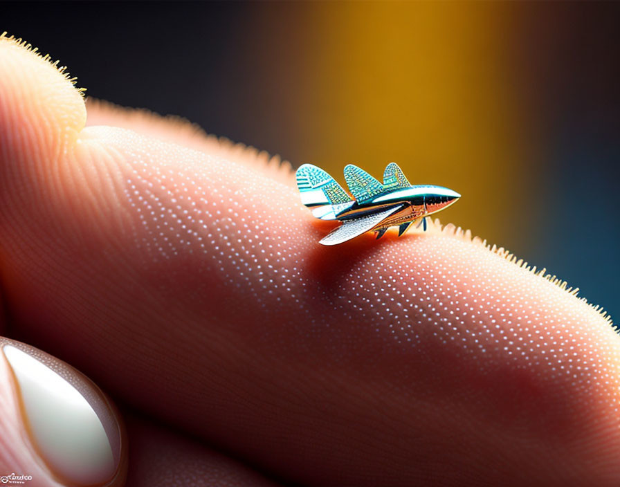 Miniature plane pin on fingertip against colorful bokeh.