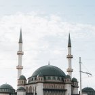 Mosque with Green and Blue Domes and Twin Minarets Against Cloudy Sky