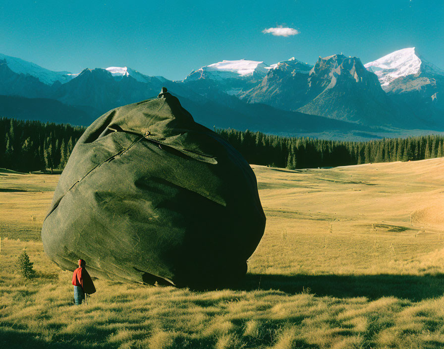 Red person near massive black object in mountain landscape