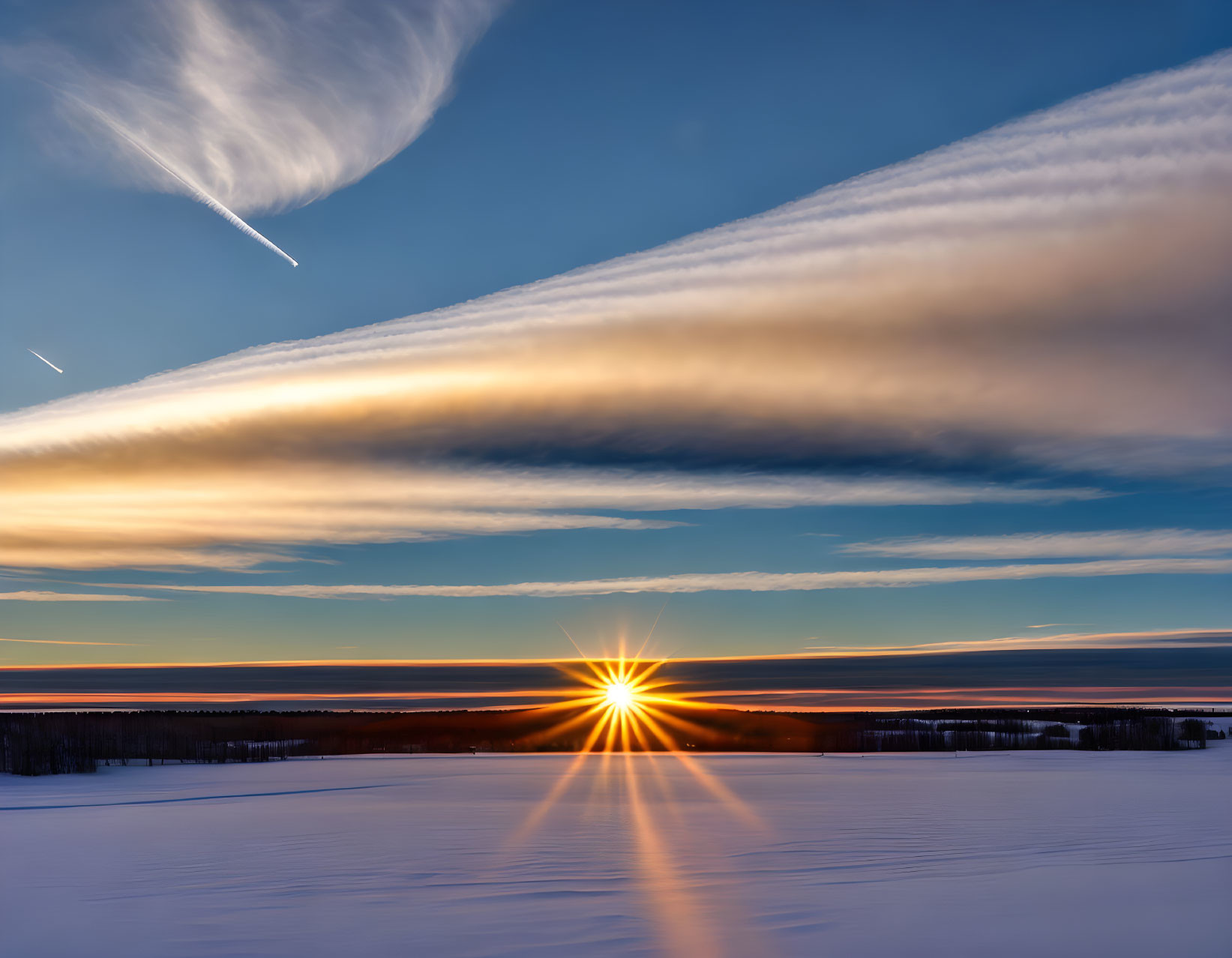 Vibrant sunset over snowy landscape with streaked clouds