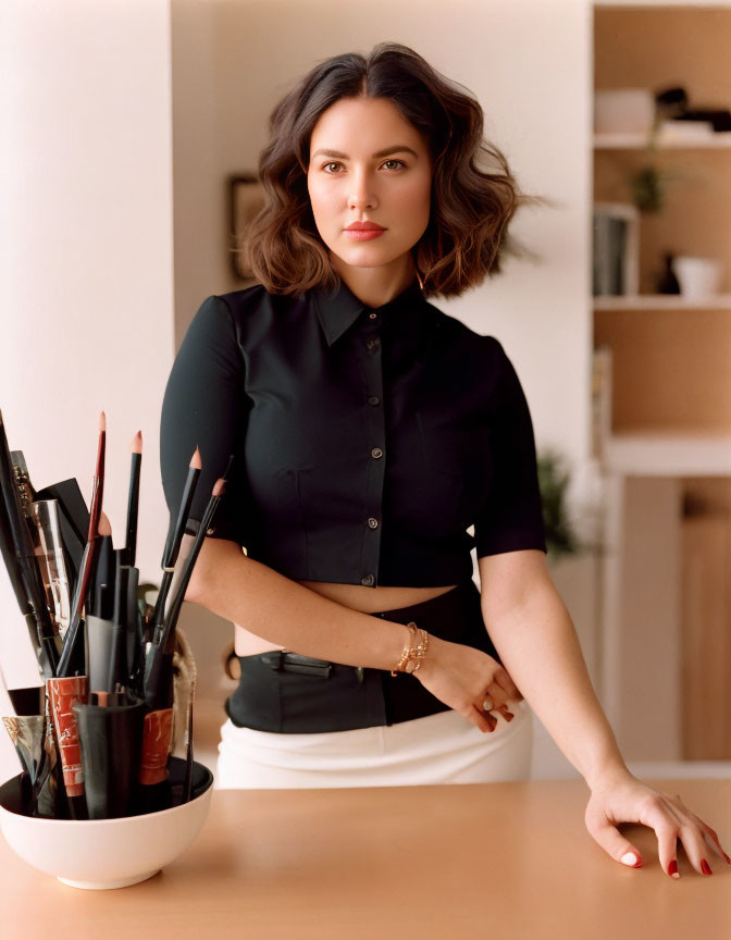 Confident professional woman with medium-length hair at desk in dark blouse.