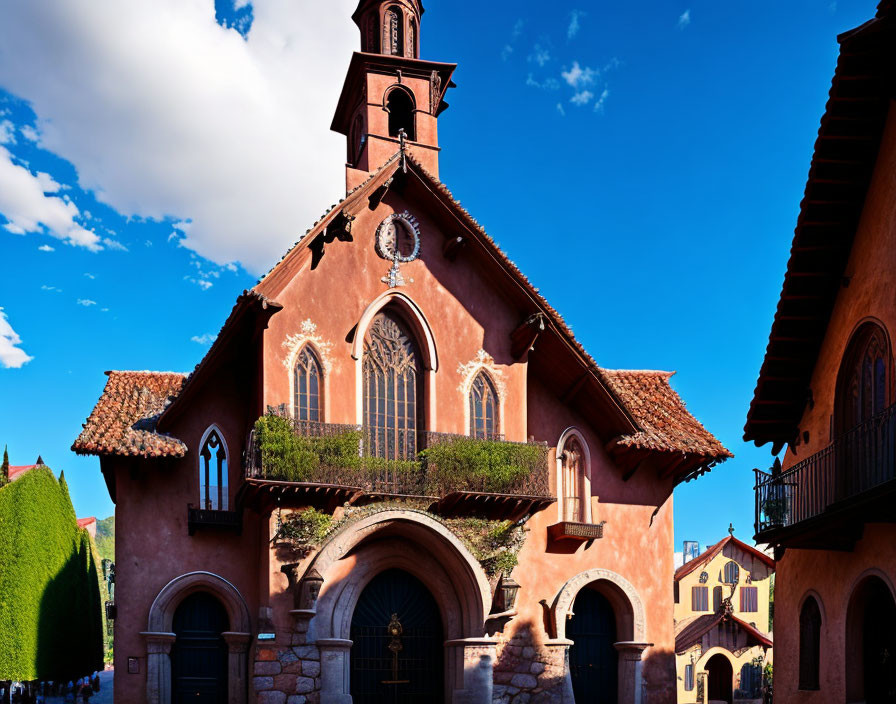 Terracotta-colored church with arched doorways and windows under a deep blue sky